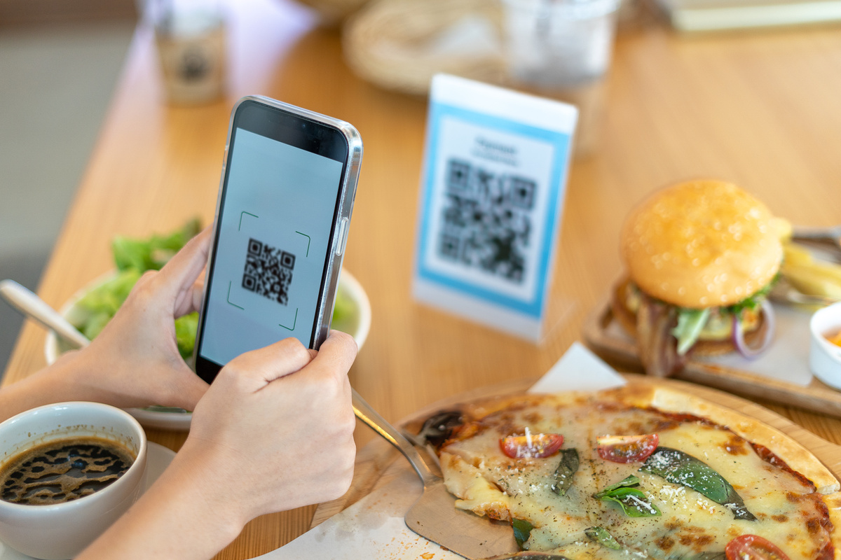 Woman's hand uses a phone to scan a qr code in a restaurant